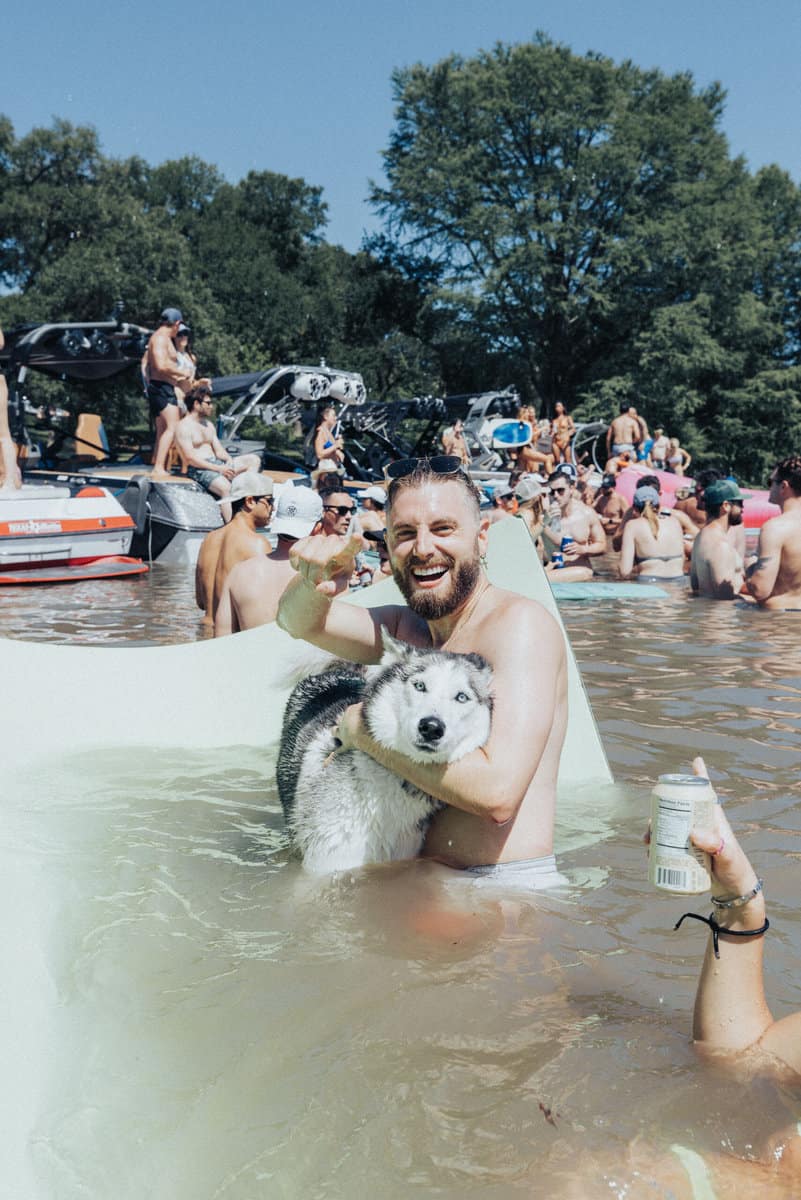Man at lake party in water with husky